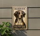 A metal sign with a picture of a dog, mounted on a wall, with the text "HARRIER DOG" below the image.