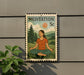 A metal medallion with a woman in a meditative pose, surrounded by a natural landscape, is displayed on a wall.