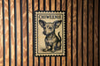 A small chihuahua dog is depicted on a wooden surface, with a black and white stamp-like design above it.
