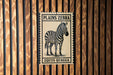 A poster of a zebra is displayed on a wooden wall.