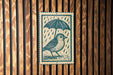 A bird standing under an umbrella, depicted in a wood-paneled setting.