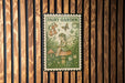 A metal sign with a fairy illustration and the text "Fairy Garden" is displayed against a wooden background.