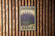 A vintage-style metal sign with the word "LAVENDER" and "HEDGE" printed on it, mounted on a wooden wall.