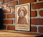 A sign featuring a portrait of a Labradoroodle dog is mounted on a brick wall.