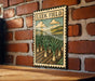 A vintage-style metal sign with a field of onions and a cloudy sky is mounted on a brick wall.