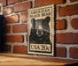 A wooden frame with a black and white illustration of a black bear on a brick wall.