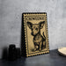 a small dog illustration on a decorative plate or frame, placed on a table next to some black camera lenses.