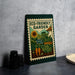 a green and white poster or sign with a garden scene, including a sunflower, carrots, and a house, placed on a gray countertop next to some black containers.