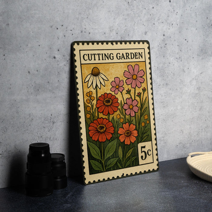 A metal stamp with a colorful illustration of flowers and plants, labeled "Cutting Garden", is displayed on a table.