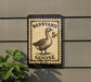 A sign featuring a goose on a postage stamp, mounted on a wall.