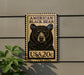 A wooden sign with a black bear image and text, mounted on a wall.