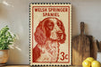 A Welsh Springer Spaniel dog is depicted on a red and white postage stamp, which is placed on a wooden surface next to a wooden cutting board and some lemons.