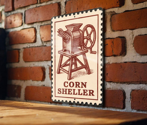 A metal sign with a vintage-style illustration of a corn grinder is mounted on a brick wall.