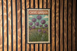 A vintage-style metal sign with a floral illustration of purple flowers is mounted on a wooden wall.