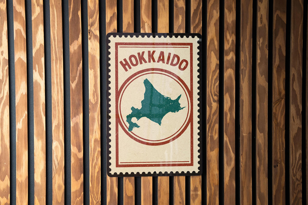 A vintage-style metal sign with the text "Hokkaio" and a map of Japan, mounted on a wooden wall.