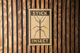 a sign with the word "STICK" and "INsect" printed on it, mounted on a wooden wall.