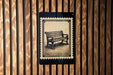 A black and white illustration of a bench is displayed on a wooden wall, framed by vertical slats.