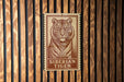 A sign featuring a tiger's portrait is mounted on a wooden wall.