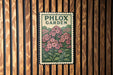 A vintage-style metal sign with a floral illustration is mounted on a wooden wall.