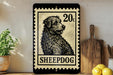 A metal sign with a black and white illustration of a dog, resembling a postage stamp, is displayed on a shelf next to a wooden cutting board and some lemons.