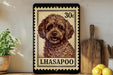 A framed image of a poodle dog, with a stamp-like border, is displayed on a shelf next to a wooden cutting board and some lemons.