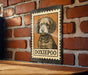 A metal sign featuring a dog illustration is mounted on a brick wall.