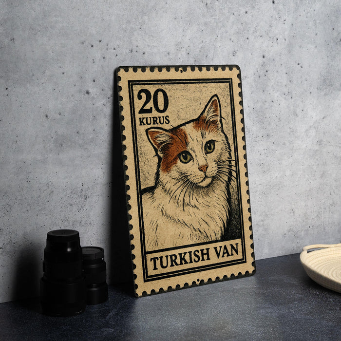 A Turkish postage stamp featuring a cat illustration, placed on a table next to some black camera lenses.