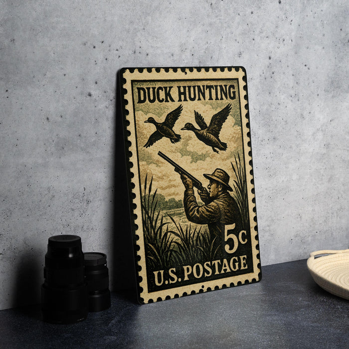 A vintage duck hunting postage stamp is displayed on a table, featuring a man aiming a rifle at ducks in flight.