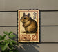 A Chinese hamster stamp is displayed on a wall, with a plant visible to the left.