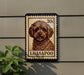 A stamp-like sign featuring a dog's portrait, mounted on a wall next to a plant.