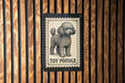 A sign featuring a poodle illustration and the text "TOY POODLE" is displayed on a wooden wall.