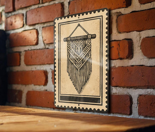 A decorative metal sign with a hanging pattern is mounted on a brick wall.