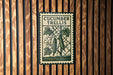 a metal sign with the text "CUCUMBER TRELLIS" and an illustration of a cucumber plant with leaves and a flower.