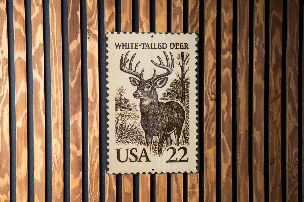 A white-tailed deer stamp from the United States, featuring a detailed illustration of the deer in a wooded setting.