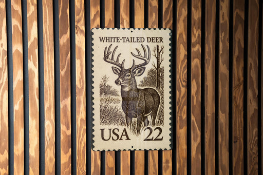 A white-tailed deer stamp from the United States, featuring a detailed illustration of the deer in a wooded setting.