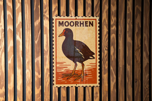 a wooden wall with a vintage-style stamp or postcard featuring a black bird, possibly a moored bird, and the word "MOORHEN" written on it.
