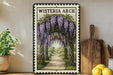A framed illustration of a wisteria arch with purple flowers, hanging over a path, is displayed on a shelf next to a wooden cutting board and a potted plant.
