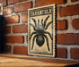 A framed poster of a tarantula is displayed on a brick wall.