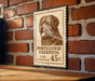 A Portuguese Sheepad dog stamp is displayed on a brick wall, with a wooden table below it.