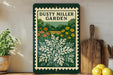 a framed poster of a garden with a variety of flowers and plants, placed on a shelf next to a wooden cutting board and some kitchen utensils.