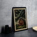 a framed illustration of a barn with a cloudy sky in the background, placed on a table next to some black camera lenses.