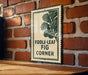 a sign with the text "FIDDLE-LEAF FIG CORNER" on a brick wall.