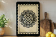 a framed black and white floral design on a shelf, with a wooden cutting board and a potted plant nearby.