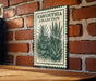A metal sign with a green border and a drawing of a cactus plant is mounted on a brick wall.