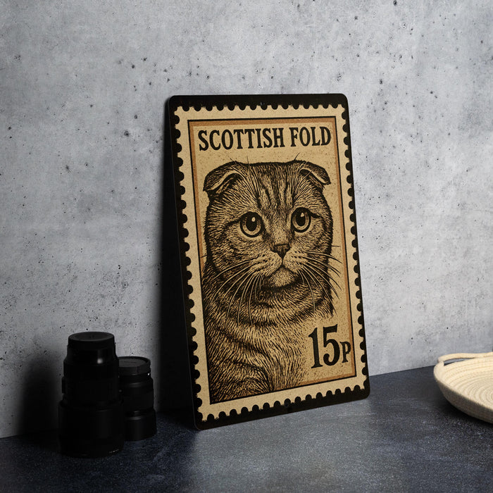 A framed Scottish fold postage stamp featuring a cat's face is displayed on a table.