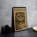 A framed Scottish fold postage stamp featuring a cat's face is displayed on a table.