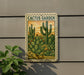 A vintage postage stamp featuring a cactus garden design, mounted on a wall next to a plant.