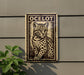 a stamp-like sign with a picture of a cat, mounted on a wall next to a plant.