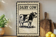a decorative sign with a cow illustration, placed on a wooden surface next to a wooden cutting board and some lemons.