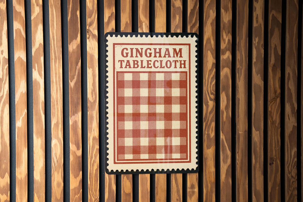 A red and white checkered tablecloth is hanging on a wooden wall.